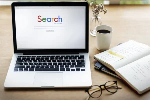 Gambar sebuah laptop yang menampilkan dashboard Google Search Console, ditemani buku catatan dan kacamata di meja kerja - Mentor Juara